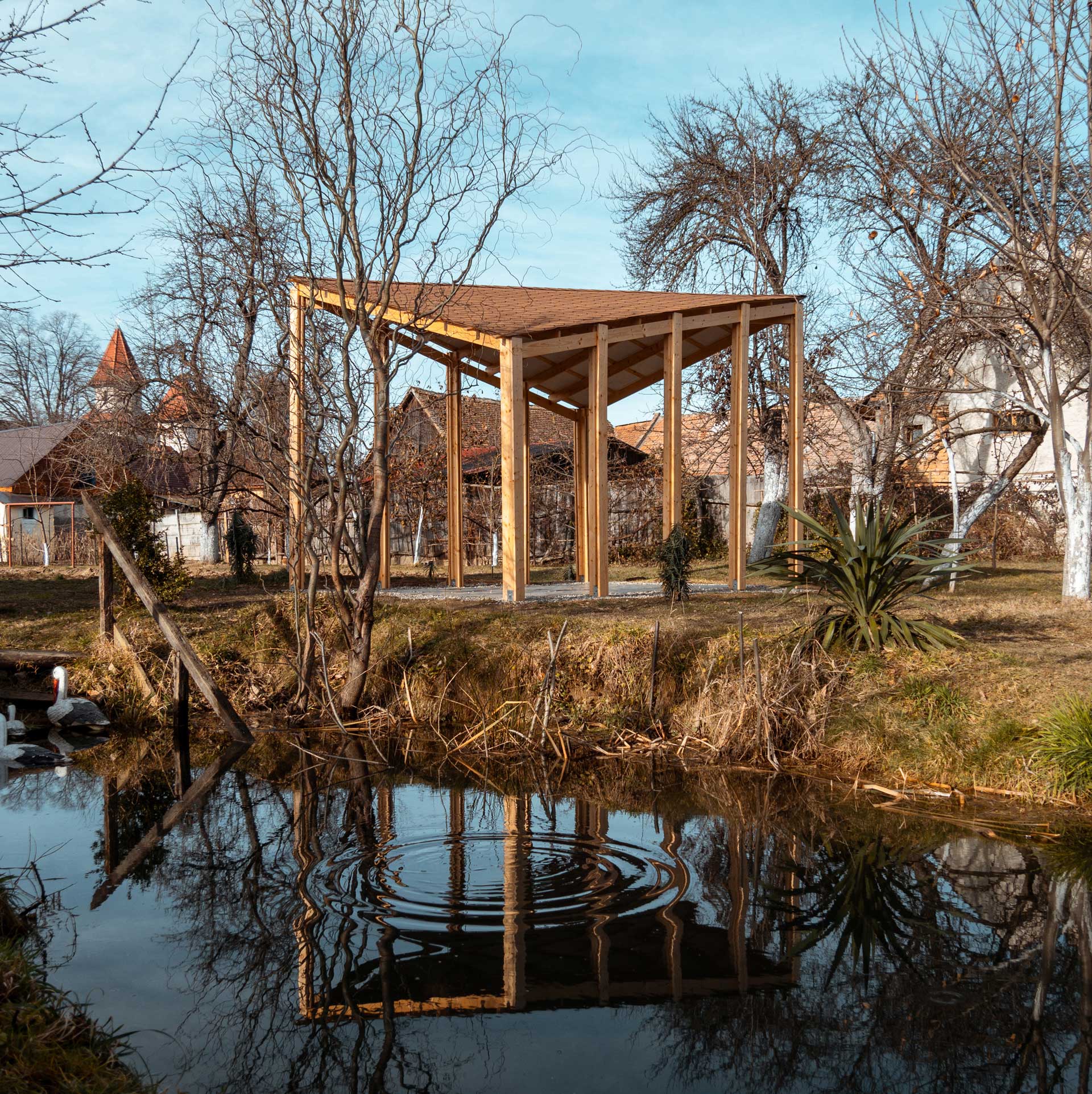 Wooden pavilion we built ourselves in the backyard, reflected in the pond.